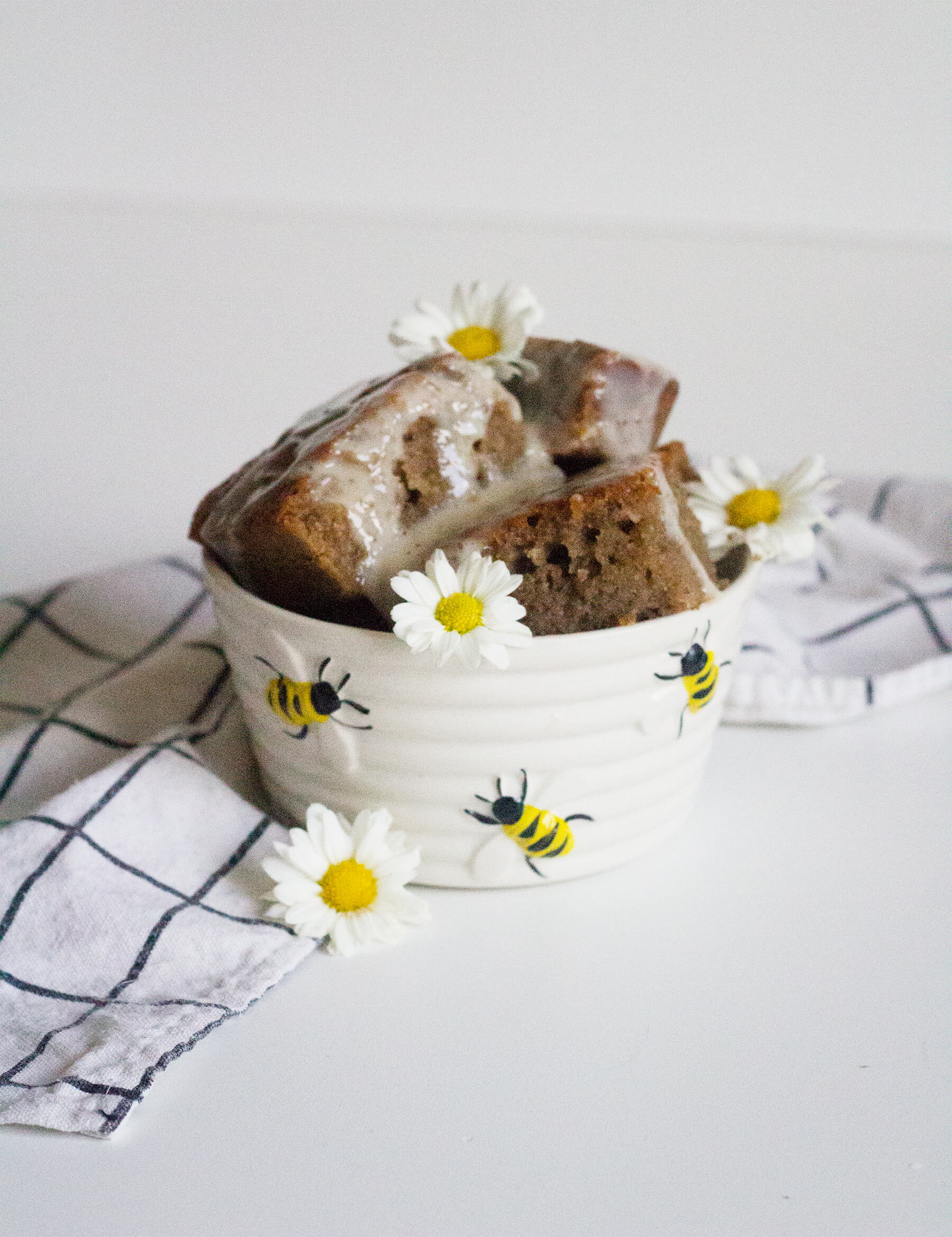 Bolo de mel com calda de coco em um pequeno pote de abelhas e mini margaridas