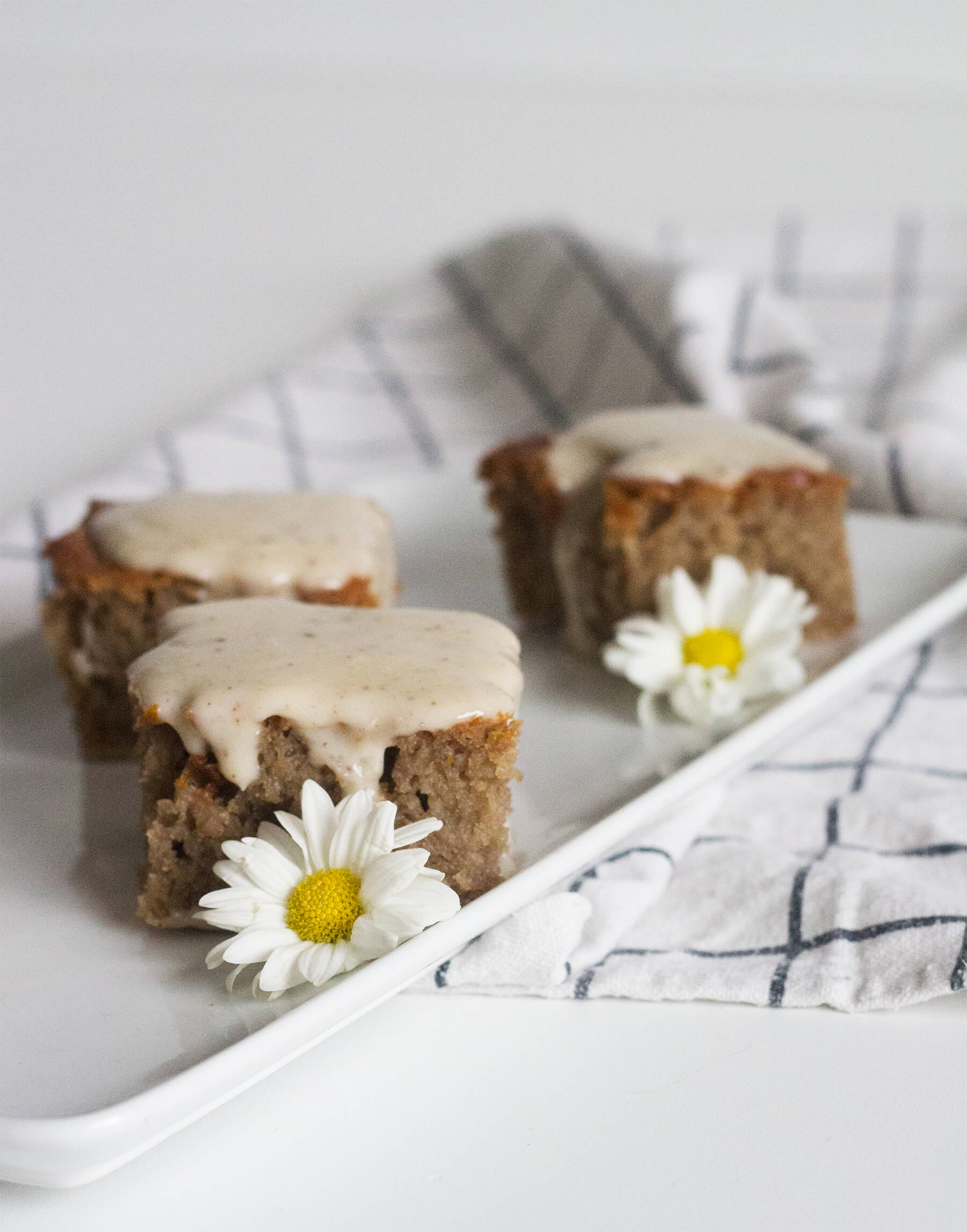 Bolo de mel com calda de coco em uma travessa em pequenos pedaços, decorado com margaridas