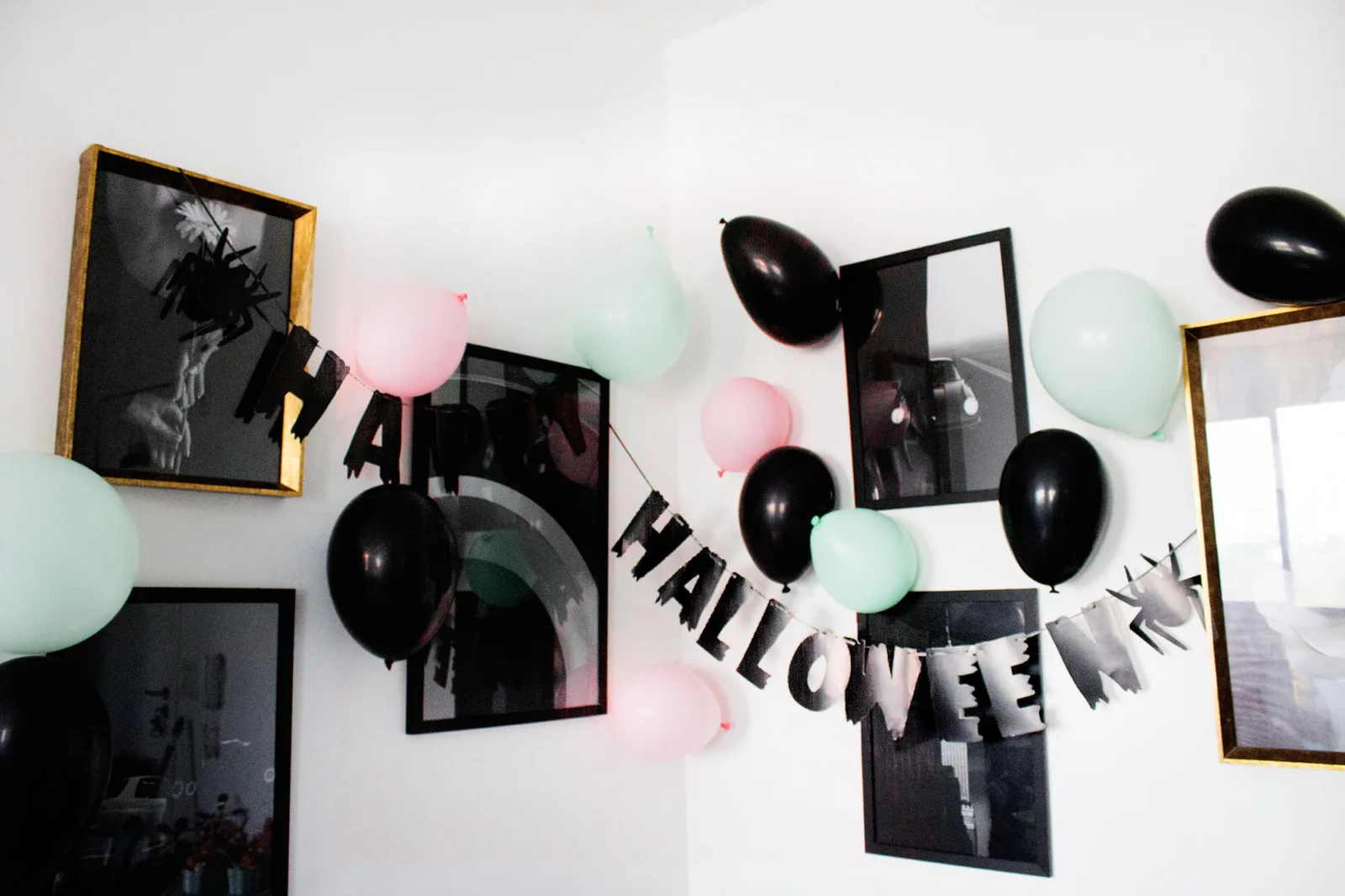 bexigas preto, rosa e verde e uma faixa de hallowen preta na parede